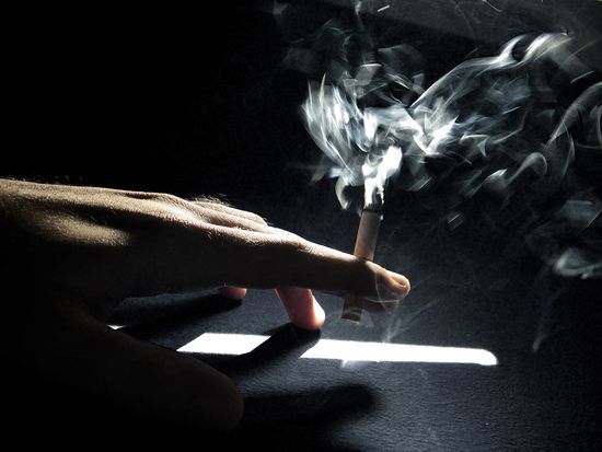 Fotografía de una mano sujetando un cigarrillo encendido