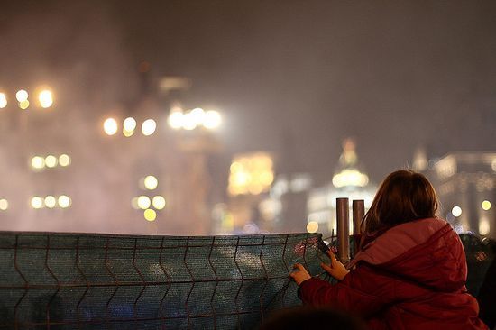 Fotografía de una niña frente a una valla en una ciudad