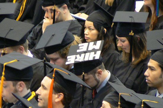 Fotografía de una graduación norteamericana con un estudiante que ha escrito "Hire me" en su birrete