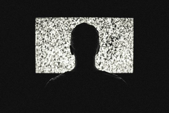 Fotografía de un hombre frente a un televisor que emite electricidad estática
