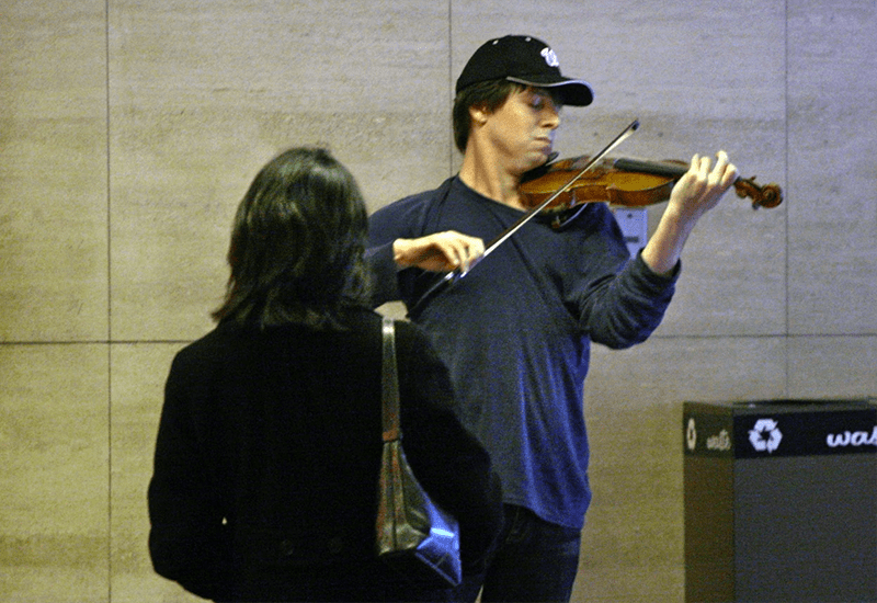 Fotografía de un músico ambulante tocando el violín en el transporte público