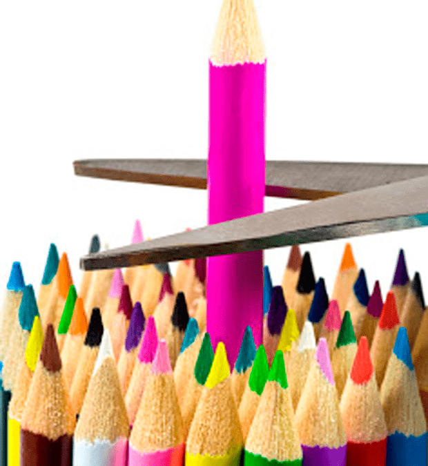 Fotografía de unas tijeras recortando a un lápiz de color que sobresale del resto