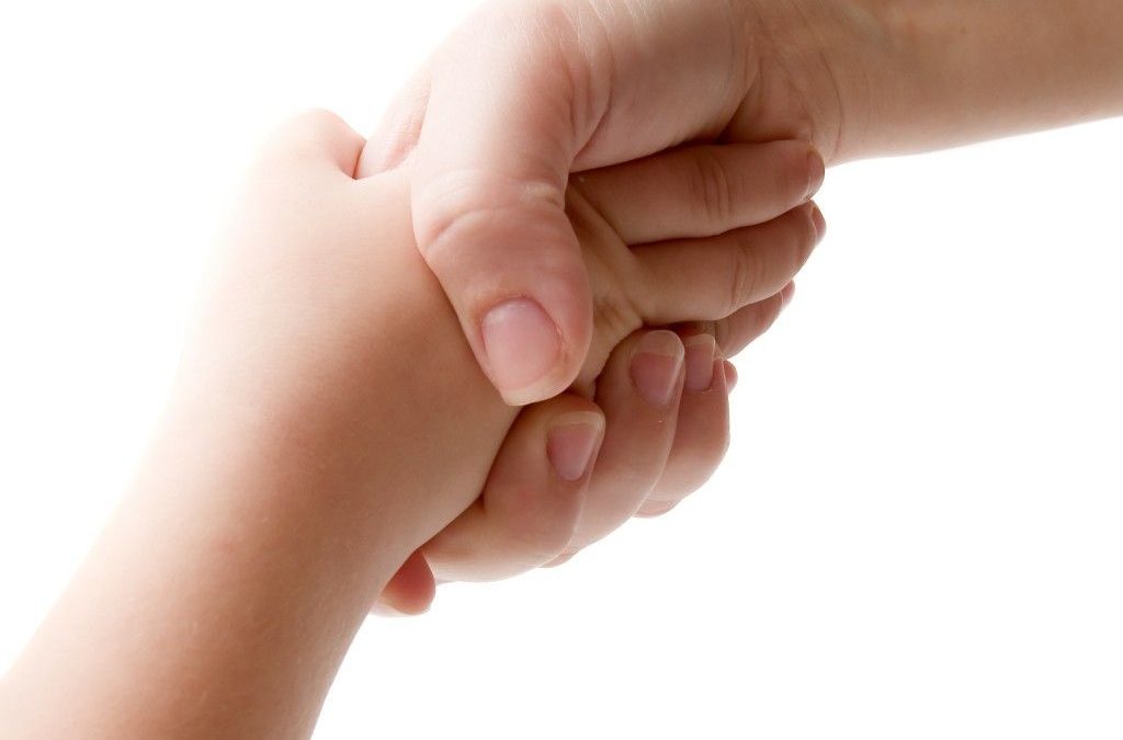 Fotografía de una mano adulta sosteniendo una mano de bebé