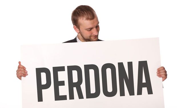 Fotografía de un hombre con un cartel que dice 'Perdona'