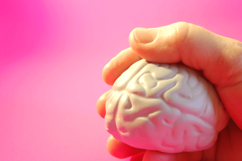 Ilustración de una mano sujetando un cerebro de juguete